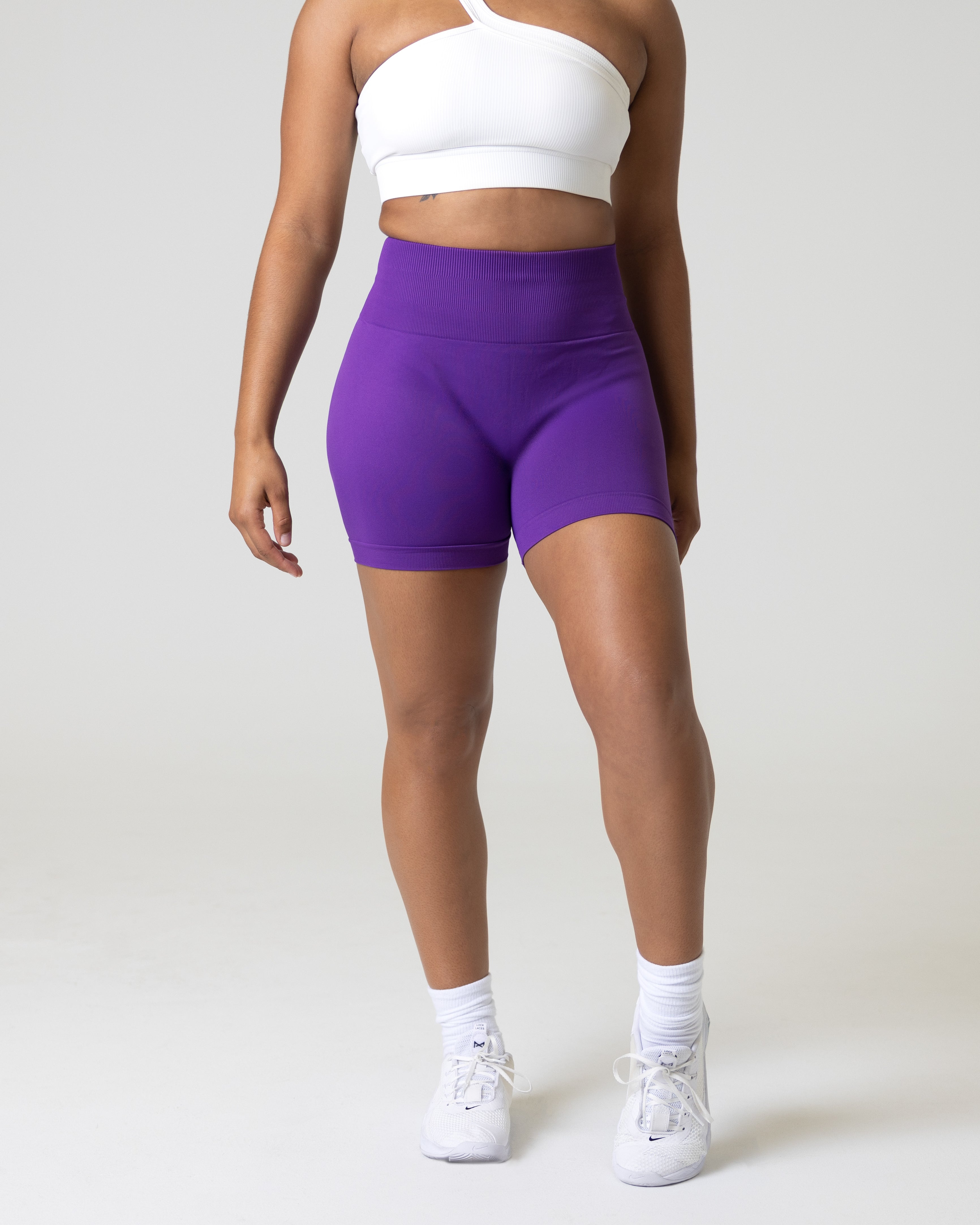 A woman wearing purple gym shorts for women scrunch beam